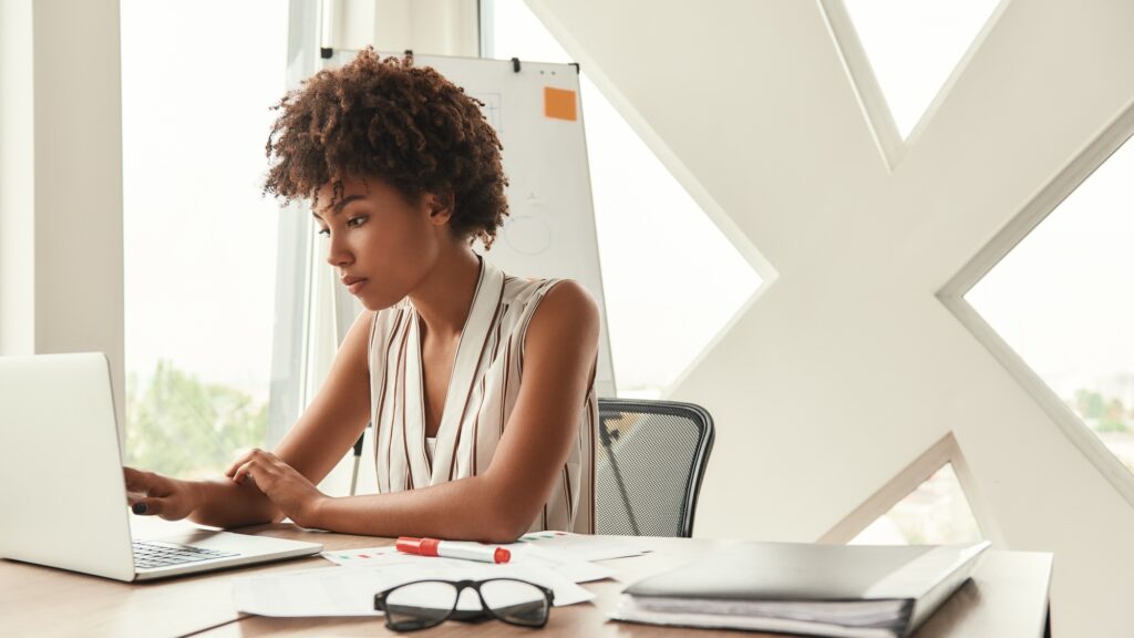 Business expert. Beautiful afro american woman working with laptop while sitting in the modern