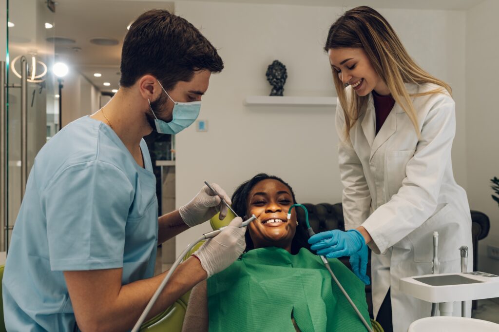 Dentist providing dental care treatment to a african american female patient
