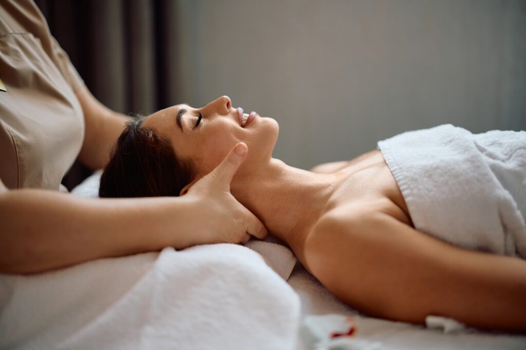 Smiling woman enjoying in relaxing massage at wellness spa.